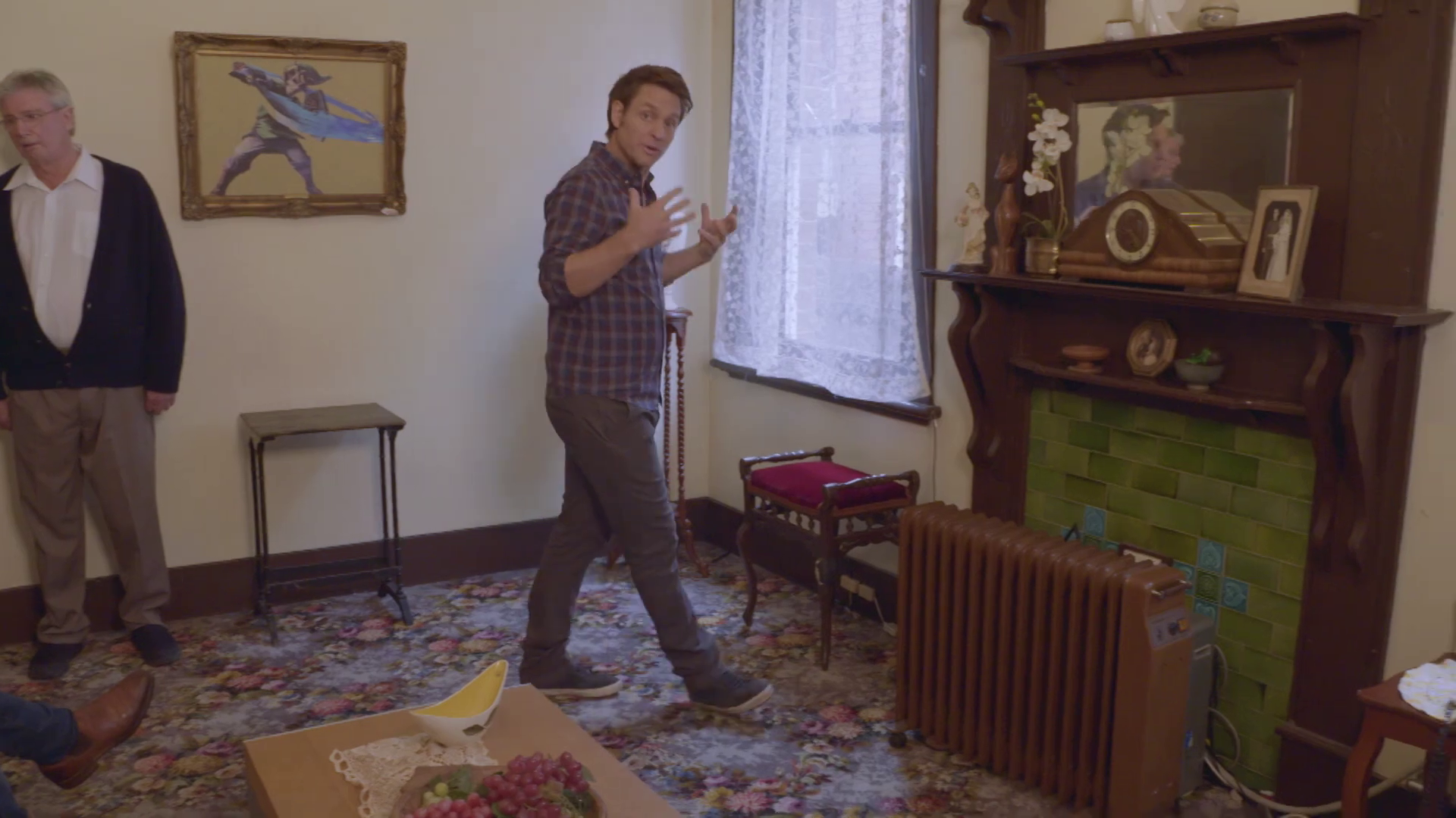 Julian Morrow explaining something in a fancy-ish old house. An illustration of Link from the Zelda games is hung up in an ornate frame in the background.